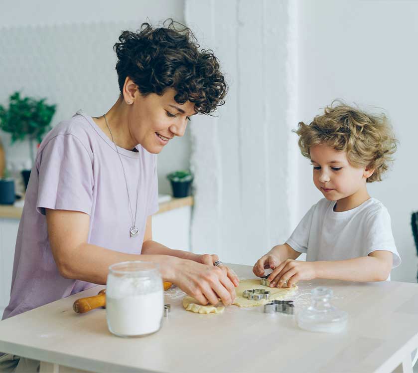 Woman and child making cookies together at a kitchen table.