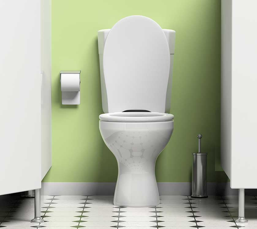 White toilet against a green wall with a toilet brush holder on a white floor.