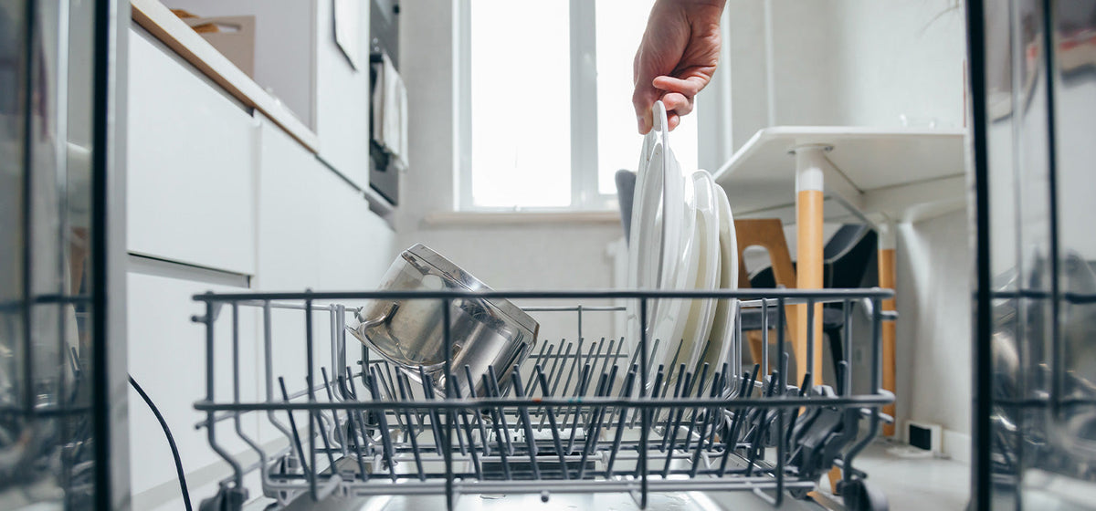 Person loading a dishwasher in a kitchen