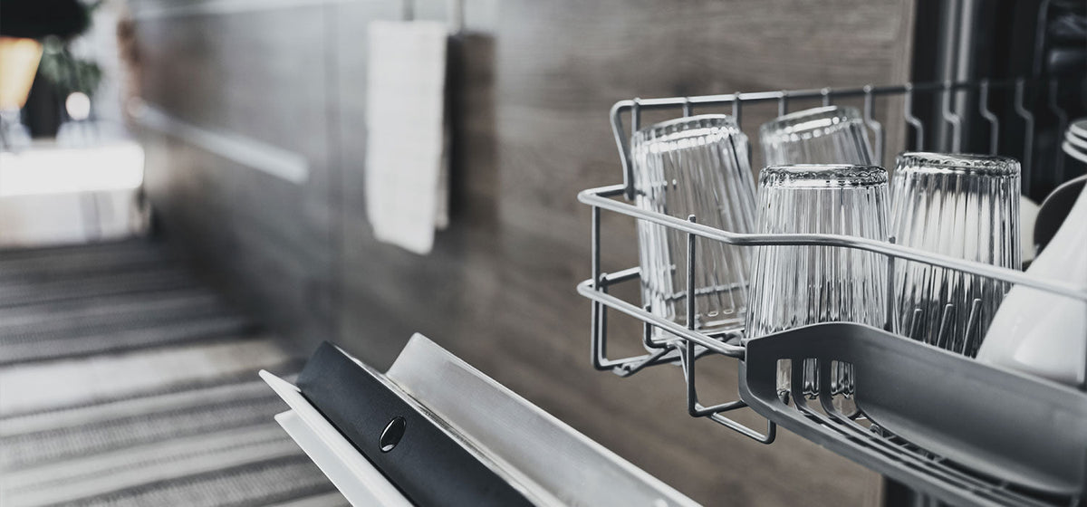 Open dishwasher with clean glassware in a hard-water kitchen