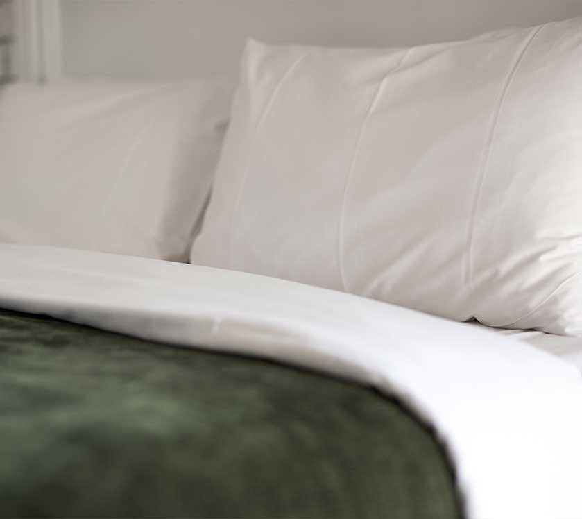 Close-up of a bed with white bedding and pillows.