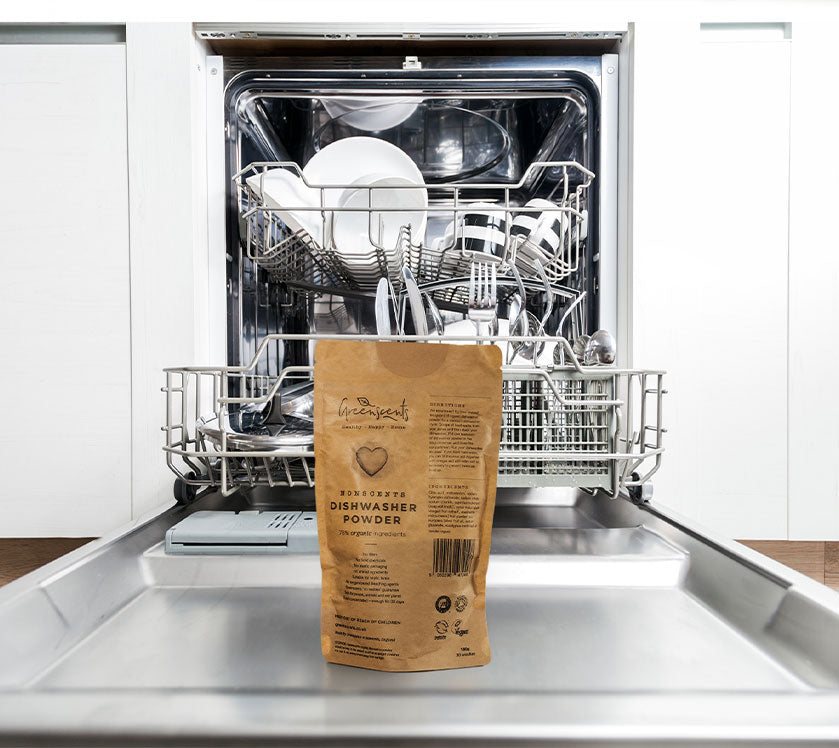 Bag of greenscents dishwasher powder in front of an open dishwasher with clean dishes.