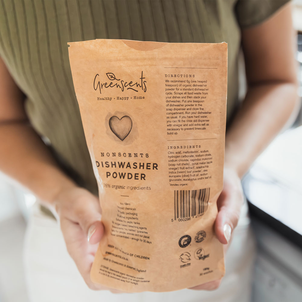 Person holding a package of GreenScents dishwasher powder
