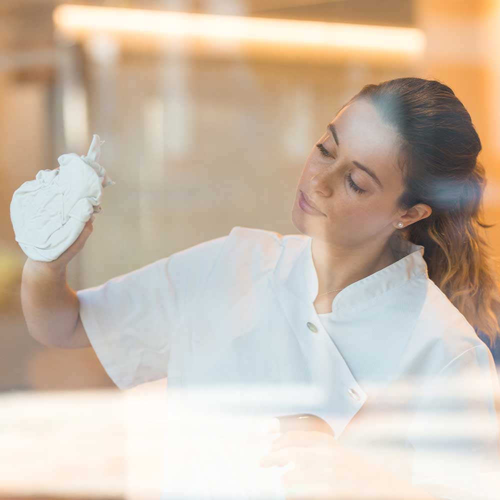 Woman holding a white heart-shaped object in a softly lit room