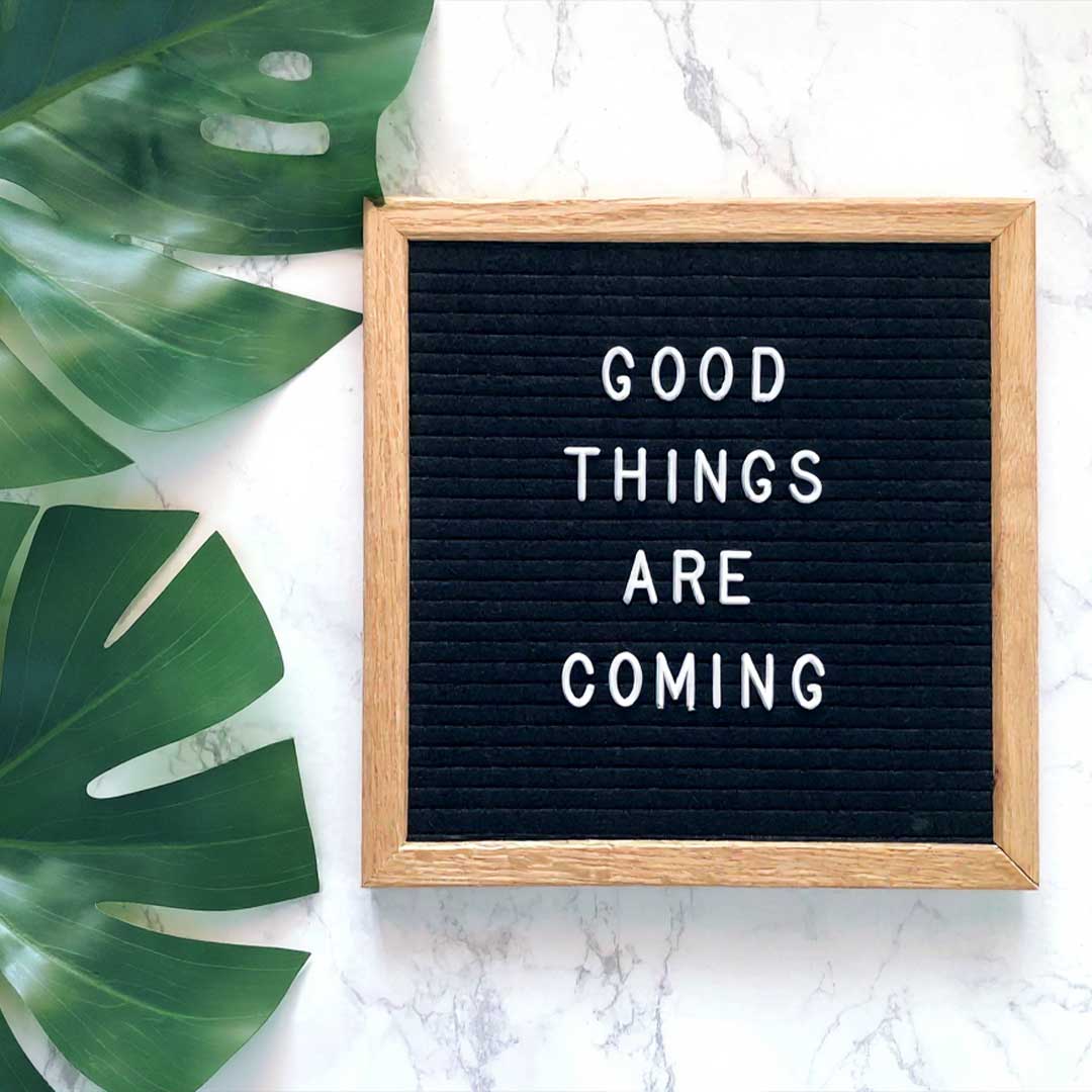 Letter board with 'Good things are coming' text on a marble surface with a leaf.