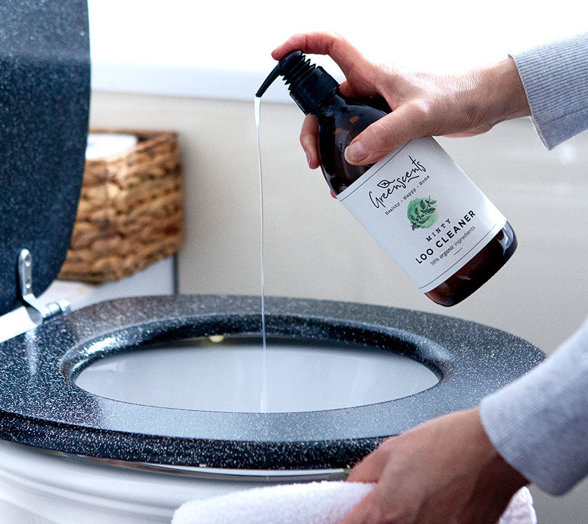 Person using a bottle of greenscents  toilet cleaner on a toilet bowl