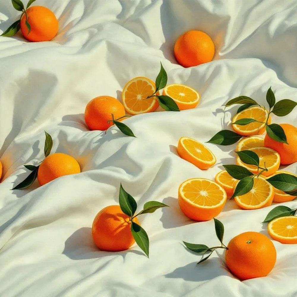 Oranges with leaves scattered on a white fabric background