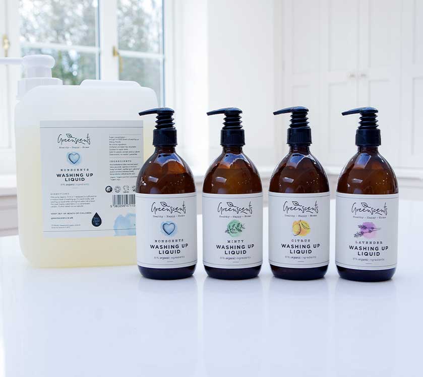 Set of five bottles of greenscents washing up liquid on a white surface with a window in the background.